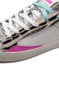 Sneaker ricoperto di glitter con un upper in materiali misti, caratterizzato da dettagli a stampa animale, lato in pelle grigia e un accento in suede rosa.