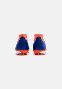 Botas de fútbol azules con un collar tipo calcetín naranja y suela blanca. Presentan un material texturizado y tacos rojos para mejorar el agarre en el césped.