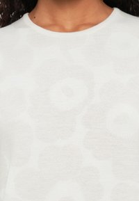 Weißer Pullover mit strukturiertem Blumenmuster, rundem Ausschnitt und leichtem Strickstoff für Atmungsaktivität.
