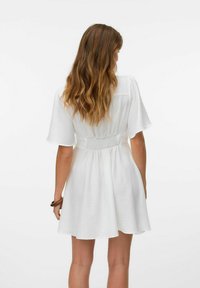 Abito bianco con maniche corte, aderente in vita con dettagli arricciati, gonna fluente. Texture morbida, design casual.