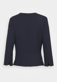 Blazer bleu marine sur mesure avec manches longues, coupe droite et fentes au dos pour faciliter les mouvements. Tissu lisse, design minimaliste.