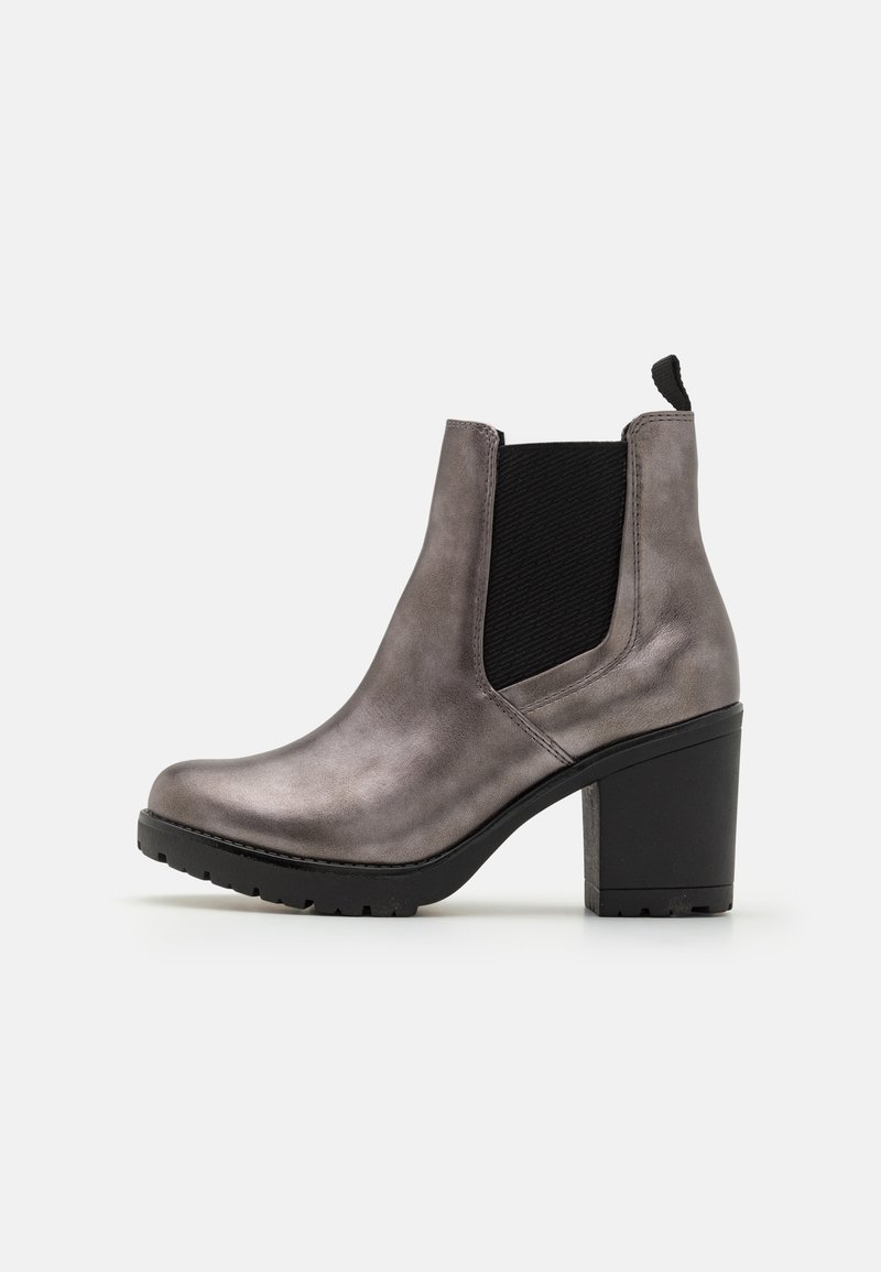 Bota de tobillo gris metálico con puntera redondeada, paneles elásticos negros y un tacón grueso. Cuenta con una lengüeta para facilitar su uso y suela texturizada.