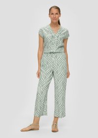 Lichtgroene jumpsuit met een geometrisch wit patroon, korte mouwen, een V-hals en een ontspannen pasvorm. Lichtgewicht stof en enkelhoogte.