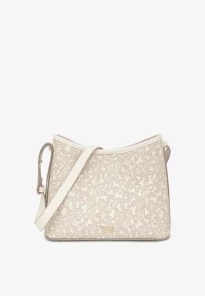 Bolso beige con un patrón texturizado, que cuenta con una correa de cuero suave y herrajes en tono dorado. El nombre de la marca "TOUS" aparece en la parte frontal.
