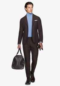 Brun randig kostym med en ljusblå polotröja. Tillbehören inkluderar en mörkbrun läderväska och bruna finskor. Slät, skräddarsydd look.