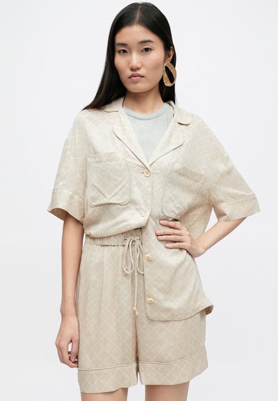 Bežová košeľa s gombíkmi a šortky so diamantovým vzorom, s krátkym rukávom, elastickým pásom a dvoma prednými vreckami.