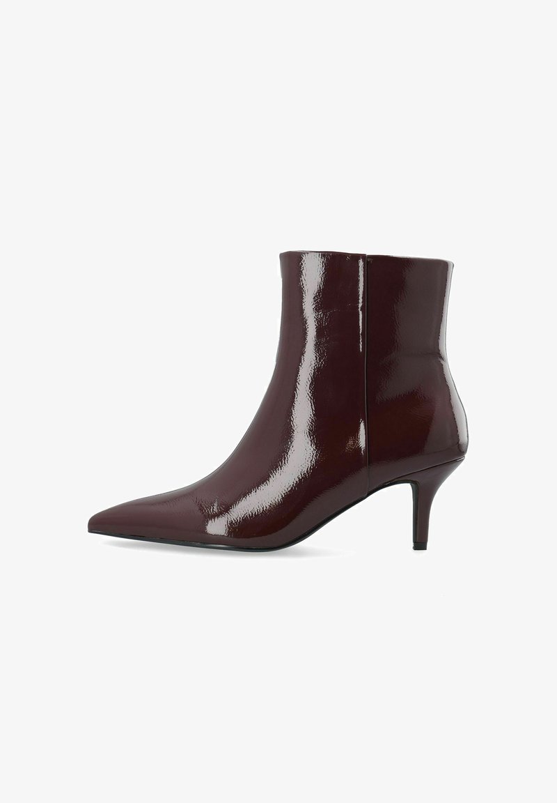 Bottine en cuir verni marron foncé brillant, bout pointu et petit talon aiguille sur fond blanc.