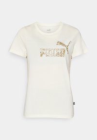 Camiseta corta de manga con cuello redondo en crema, hecha de algodón, que presenta un atrevido logo dorado de "PUMA" y una gráfica de un puma saltando impresa en el frente.