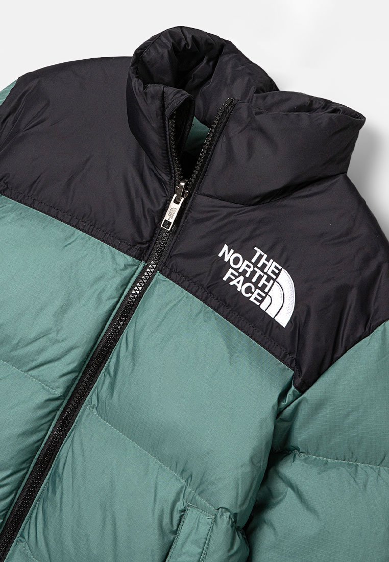 Puffjacke mit einem schwarzen oberen Abschnitt und einem türkisfarbenen unteren Abschnitt. Verfügt über einen hohen Kragen, einen Frontreißverschluss und das weiße Logo "The North Face".