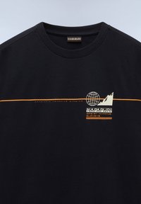 Sort bomulds t-shirt med et hvidt og orange grafisk design, der inkluderer en globus, bjergsilhuet og "Napapijri" logo.