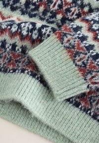 Strikket sweater med mønstret design i marineblå, rød og hvid, med grønne ribkanter og en blød, tekstureret overflade.