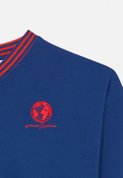 Niebieska bluza z czerwono-niebieskim paskowanym kołnierzem, z czerwonym haftowanym globusem i kursywnym napisem poniżej na piersi.