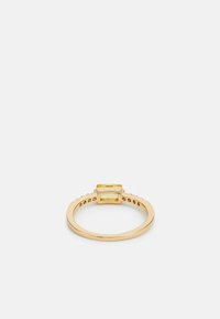 Anello in oro con due gemme gialle rettangolari impostate su una semplice fascia con accenti testurizzati sui lati.