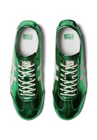 Zielone metaliczne sneakersy z białymi akcentami, z wiązanym designem i zaokrąglonym noskiem. Logo widoczne na języku i wkładce.
