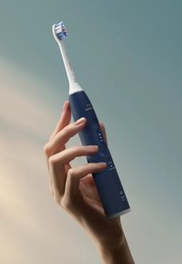 Brosse à dents électrique avec une tête blanche, un manche en plastique bleu, des boutons d'alimentation et de mode, et trois voyants lumineux à l'avant.