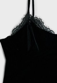 Sort fløjl camisole med delikat blondekant, justerbare stropper og tætsiddende design, med en glat overflade og ingen synlige hardwareelementer.