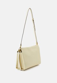 Krämfärgad läderaxelväska med rektangulär form, justerbar rem och detaljer i guld. Slät textur och minimalistik design.