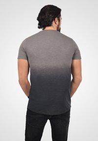 Kortærmet T-shirt med et gradient design fra lysegrå til mørkegrå. Blød tekstur med en afrundet bund og subtile syninger.