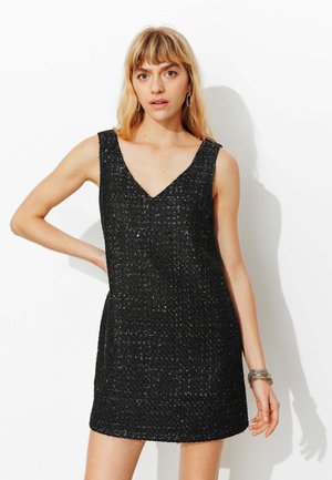 Robe noire sans manches avec un col en V, tissu texturé avec des accents scintillants, et une silhouette cintrée arrivant à mi-cuisse.
