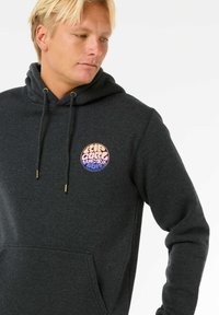 Felpa grigia con tasca frontale, cappuccio con cordino e un logo circolare multicolore sul lato sinistro del petto. Tessuto morbido con una texture liscia.