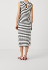 Pruhované černobílé bezramínkové šaty midi délky s kulatým výstřihem na zádech. V kombinaci s růžovými sandály na klínku.