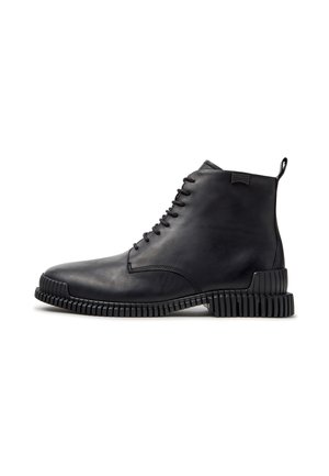 Schwarzer Lederknöchelstiefel mit Schnürung vorne und profilierter Sohle und Ferse, seitlich mit Camper-Logo und Zuglasche hinten.