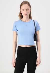 Light blue cropped t-shirt made of cotton. Features a round neckline and short sleeves, with "HUGO" embroidered in contrasting thread on the chest.