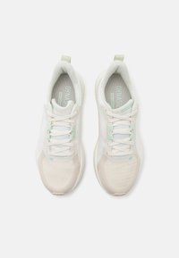 Hvite joggesko med mesh-overdel, lyse mintfargede detaljer, teksturert tåhette og flate lisser. Har polstret krage og fleksibel såle.
