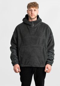 Pullover in pile con cappuccio, realizzato in materiale grigio scuro testurizzato, con zip centrale, polsini elasticizzati e un piccolo patch con logo sul petto.