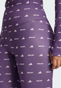 Fialové legíny s bielym vzorom loga "MOON BOOT" a trojuholníkovými motívmi. Vyrobené zo strečového materiálu s hladkou textúrou. Obsahujú priliehavý strih a švy.