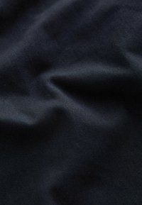 Crni materijal s glatkom teksturom, koji sadrži suptilne dijagonalne linije i blage bore, prikazuje izdržljivi, tkaninski materijal.
