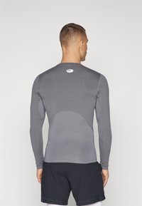Graues langärmliges Sportshirt mit feuchtigkeitsableitendem Stoff und taillierter Passform. Verfügt über eine glatte Textur und ein Logo im oberen Rückenbereich.