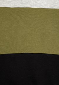 Genser med tre horisontale striper: lys grå øverst, olivengrønn i midten og svart nederst. Myk strikket tekstur.