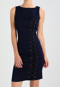 Ärmös marinblå klänning med en central svart snörningsdetalj som löper vertikalt från bröstet till fållen.