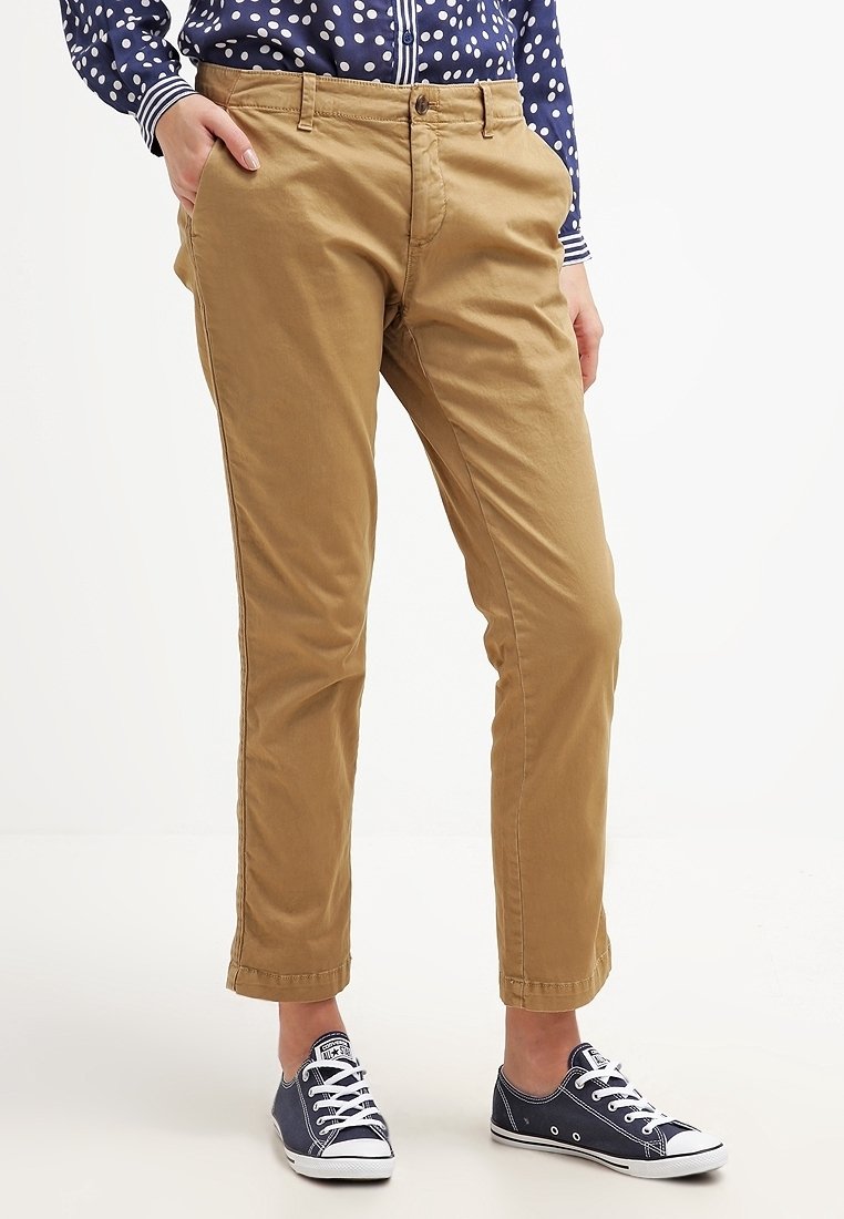 Pantalon kaki en coton, à coupe droite, avec poches avant et fermeture à bouton. Associé à des baskets en toile bleu marine.