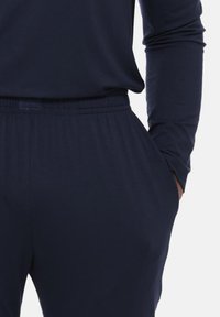 Completo da soggiorno blu navy composto da un top a maniche lunghe e pantaloni con vita elastica, realizzato in tessuto morbido con una texture liscia.