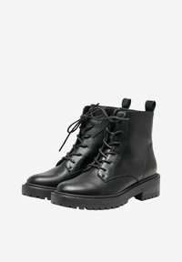 Botas de tobillo de cuero negro con punta redonda, frente con cordones y tiradores. Presentan una suela acolchada texturizada para agarre y comodidad.