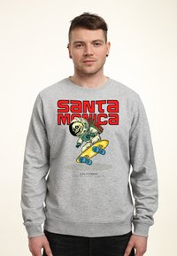 Šedá mikina s potiskem skateboardisty ve skafandru. Text zní "SANTA MONICA" červeně s žlutým skateboardem a modrými koly.
