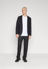 Black blazer over a white T-shirt, paired with black trousers and shiny black shoes. Smooth fabric, tailored fit, and minimalistic design.