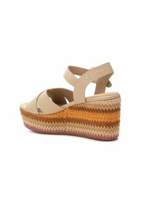 Sandali con zeppa in pelle beige con cinturini incrociati e una piattaforma intrecciata multicolore dalla superficie testurizzata. Caratterizzati da una finitura liscia e un tacco elevato.