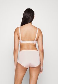 Light pink bras and shorts set featuring adjustable straps and a seamless design with a smooth, soft texture.
