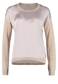 Light-colored long-sleeve top featuring a smooth front panel and contrasting textured sleeves, with ribbed cuffs and hem.