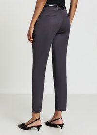 Pantalons gris ajustés avec une coupe slim, dotés d'une texture lisse, de deux poches arrière et d'une taille polie. Associés à des escarpins à talons ouverts noirs.