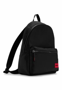Black nylon backpack with rounded shape, front zipper pocket, and red logo tag. Adjustable straps and smooth texture. Simple design.