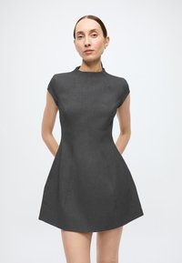Mørkegrå kjole med høj hals og korte ærmer. Den har en tætsiddende krop og en udvidet nederdel, lavet af tekstureret stof.