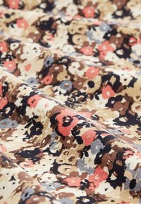 Tissu en coton avec un motif floral présentant des fleurs rouges, bleues et brunes sur un fond beige, texture douce et subtil éclat.