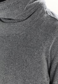 Szary, miękki, teksturowany sweter z wysokim kołnierzem o luźnym kroju, z delikatnym połyskiem i gładką powierzchnią.