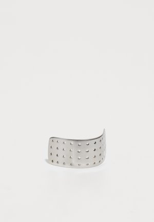 Anello di metallo argento con un design curvo e fori uniformemente distanziati su tutta la superficie. Texture liscia con finitura lucida.