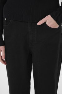 Zwarte denim broek met een rechte snit, voorzien van een voorzak en zichtbare stikseldetails. Het materiaal heeft een zachte, gestructureerde afwerking.