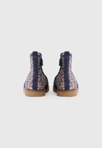 marineblaue Knöchelstiefel mit glitzernden roségoldenen Akzenten, aus Wildleder, mit runder Zehenpartie und flacher brauner Sohle, ausgestattet mit einem Reißverschluss für einfaches An- und Ausziehen.